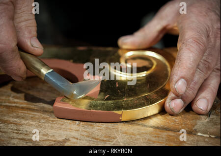 Artigiano utilizza l'agata pietra per il procedimento di brunitura. Tecnica di doratura. Foto Stock