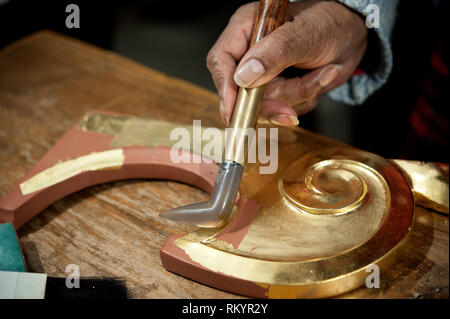 Artigiano utilizza l'agata pietra per il procedimento di brunitura. Tecnica di doratura. Foto Stock