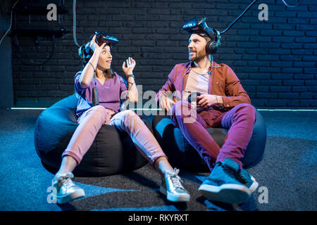 Uomo e donna con eccitato emozioni seduti insieme dopo il gioco in realtà virtuale nella riproduzione di camera Foto Stock