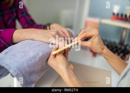 Primo piano della professional cosmetologo deposito unghie nel processo di manicure. Foto Stock