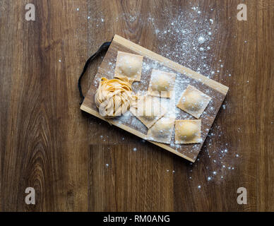 Freschi tagliatelle e ravioli su una scheda. Foto Stock