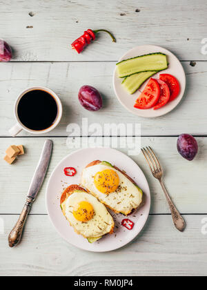La colazione brinda con verdure e uova fritte su piastra bianca, una tazza di caffè e un po' di frutta su sfondo di legno. Dieta concetto alimentare. Vista da una Foto Stock