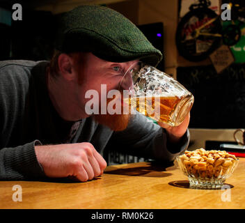 Il Barbarossa ragazzo irlandese bevande birra nel bar. Egli è forse ubriaco ma lui è molto felice! Foto Stock