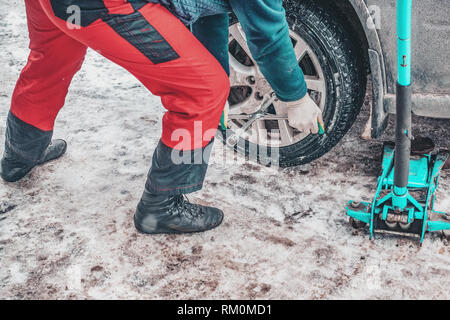 Il processo di lavoro di rimozione delle ruote dalla macchina sulla strada in inverno. Sostituzione di pneumatici invernali per l'estate. Foto Stock