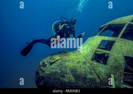 Un subacqueo nuota lungo il cockpit del relitto di una C-130 cargo aereo nelle acque del mar rosso nei pressi di Aqaba in Giordania. Foto Stock