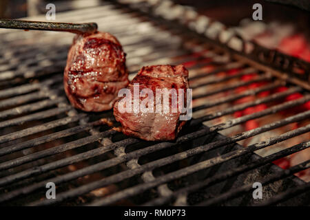 Un top bistecca di controfiletto arrostito alla fiamma su un barbecue, una profondità di campo ridotta. Carne alla griglia Foto Stock