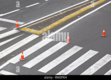 La strada dipinta con linee bianche, crosswalk e striato coni arancione Foto Stock