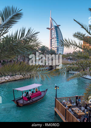 Il Burj al Arab emerge da tra le fronde di palme come barche glide passato lungo le acque del Madinat Souk di Dubai. Foto Stock