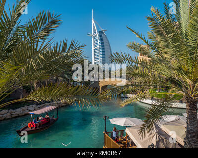 Il Burj al Arab emerge da tra le fronde di palme come barche glide passato lungo le acque del Madinat Souk di Dubai. Foto Stock