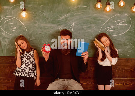 Insegnante e le ragazze gli studenti in aula, lavagna su sfondo. Bambini e insegnanti con disegnato da chalk corna. Uomo con barba urlando mentre Foto Stock