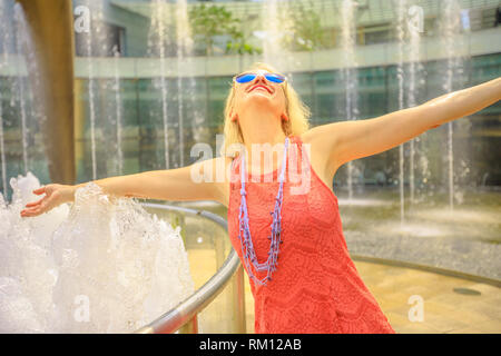 Fontana della Ricchezza a Suntec Tower la più grande fontana in Singapore. Lo stile di vita della donna a piedi e toccare l'acqua della fontana per avere fortuna. Blonde tourist Foto Stock