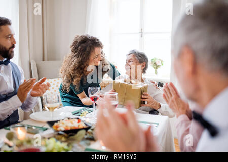 Una nonna festeggia il compleanno con la famiglia e la ricezione di un dono, il concetto di partito. Foto Stock