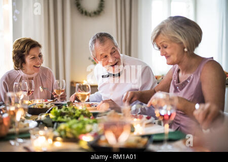 Gli anziani seduti a tavola su una famiglia indoor festa di compleanno, mangiare. Foto Stock