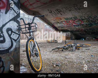 Vecchio rottame giallo biciclette sotto il cemento scale con graffiti e senzatetto rifugio del sonno Foto Stock