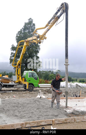 Builder utilizza una pompa per calcestruzzo per dirigere il calcestruzzo bagnato in le fondamenta di un edificio di grandi dimensioni Foto Stock