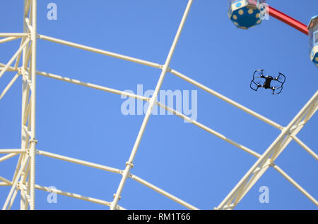 Drone con fotocamera decollare da terra e volare per prendere foto anteriore della ruota panoramica Ferris Foto Stock