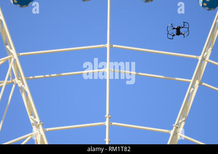 Drone con fotocamera decollare da terra e volare per prendere foto anteriore della ruota panoramica Ferris Foto Stock