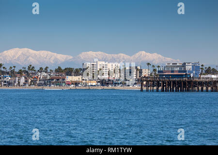 Newport Beach pier California presi da una barca al largo durante l'inverno del 2019 con cime Montagne di San Gabriel in background Foto Stock