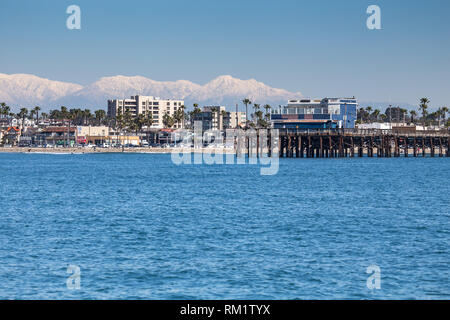 Newport Beach pier California presi da una barca al largo durante l'inverno del 2019 con cime Montagne di San Gabriel in background Foto Stock