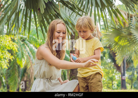 Madre e figlio utilizzare spray di zanzara.la spruzzatura di repellente per insetti sulla pelle per esterno Foto Stock