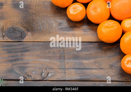 Un sacco di arancia freschi Mandarini giacciono su di un legno marrone dello sfondo. Lay piatto con frutti in una scatola di legno Foto Stock