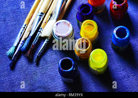 Poster i colori e i pennelli per dipingere su uno sfondo blu Foto Stock