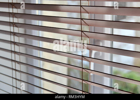 Chiudere su un veneziano di persiane in legno di fronte a una finestra Foto Stock