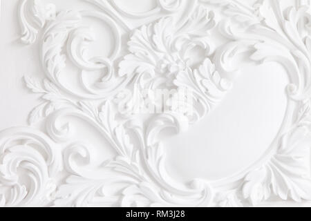 Bella ornati in bianco intonaco decorativo di modanature in studio. Il muro bianco è decorata con raffinati elementi di stucco in gesso Foto Stock