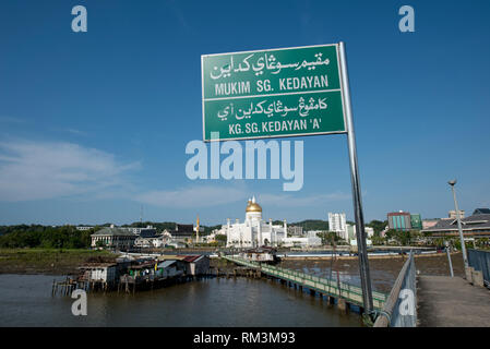 Strada segno, sul marciapiede sul fiume con opulenti Sultan Moschea di Omar Ali Saifuddien con baracche in primo piano, Kedayan River, Bandar Seri Begawan, Br Foto Stock