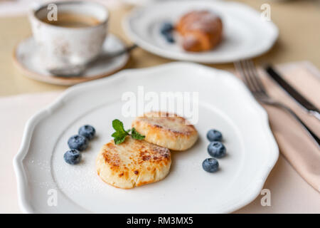 Cottage cheese frittelle o syrniki con mirtillo su piastra bianca, vista ingrandita. Russo, Ucraino cucina. Una sana colazione gustosa Foto Stock