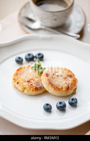 Cottage cheese frittelle o syrniki con mirtillo su piastra bianca, vista ingrandita. Russo, Ucraino cucina. Una sana colazione gustosa Foto Stock