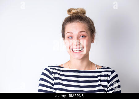 Ritratto di divertenti ridere allegro e sorridente donna bionda in abito a righe su sfondo bianco con copia spazio. Giovane ragazza gioiosa sorpresi e ope Foto Stock