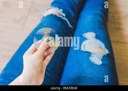 Ragazza adolescente in holey jeans tiene in mano e gioca con un dispositivo a rotazione vorticosa Foto Stock