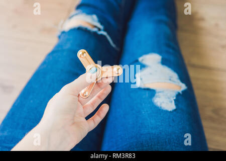 Ragazza adolescente in holey jeans tiene in mano e gioca con un dispositivo a rotazione vorticosa Foto Stock