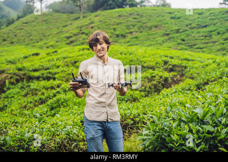 Gli uomini turista cerca di lanciare il drone in una piantagione di tè. Selezionate naturali, fresche foglie di tè tè in fattoria in Cameron Highlands, Malaysia. Ecoturismo Foto Stock