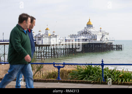 Eastbourne, East Sussex, Regno Unito. Xiii Febbraio, 2019. Regno Unito: Meteo tempo soleggiato in Eastbourne oggi con alti di 10°C. Due uomini a piedi passato la Eastbourne Pier su un luminoso e soleggiato inverni giorno. © Paul Lawrenson 2019, Photo credit: Paolo Lawrenson / Alamy Live News Foto Stock