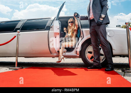 Autista aiutando vip donna o star fuori di limo sul tappeto rosso per un ricevimento Foto Stock