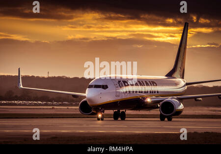 Aeroplano appartengono a Ryanair in attesa sulla pista dell'aeroporto di Gatwick in Regno Unito, al tramonto. Foto Stock