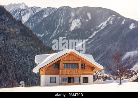 Bella solitaria casa in legno sullo sfondo di montagne innevate. Sci popolare regione Stiria, Austria Foto Stock