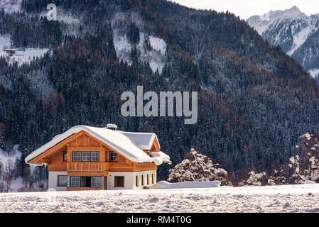 Bella solitaria casa in legno sullo sfondo di montagne innevate. Sci popolare regione Stiria, Austria Foto Stock
