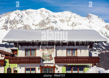 Casa di montagna con cime innevate sullo sfondo nella regione sciistica di Schladming-Dachstein, massiccio Dachstein, Liezen District, Stiria, Austria, Europa Foto Stock