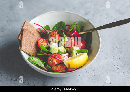 Vegetariano insalata sana è fatta di bietola in foglie, pomodori ciliegini, avocado, il succo di limone e olio di oliva in una porzione di ceramica ciotola. Foto Stock