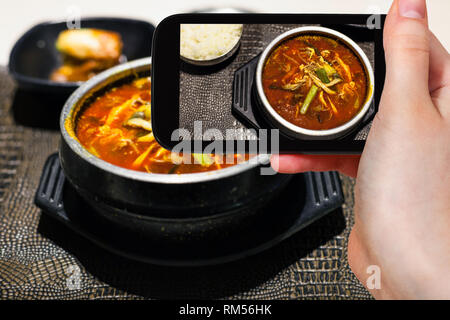 Concetto di viaggio - visitatore fotografie di cucina coreana di yukgaejang (zuppa piccante con carne di manzo, uova, funghi, amido tagliatelle, lo scalogno, felci, fagiolo sp Foto Stock