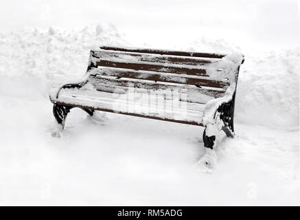 Vuoto in legno marrone panchetta outdoor su pulire il bianco della neve in inverno nuvoloso giorno vista laterale vista dettagliata Foto Stock