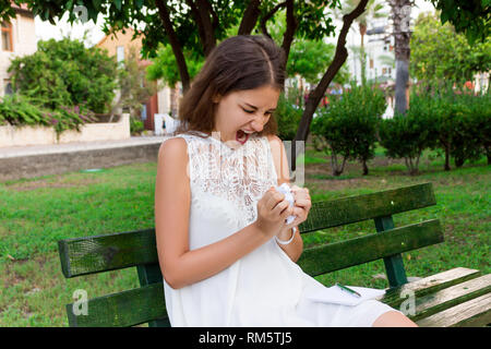 Arrabbiato e infastidito la ragazza è in possesso di carta sgualcita seduto sulla panchina del parco. Foto Stock