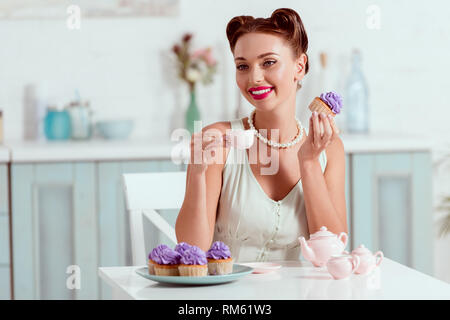Elegantemente vestito pin up girl holding tazza di caffè e dolci fatti in cupcake Foto Stock