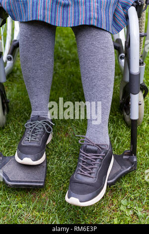 Close up foto di anziani disabili donna di piedi seduto in una sedia a rotelle, facendo una passeggiata nel parco Foto Stock