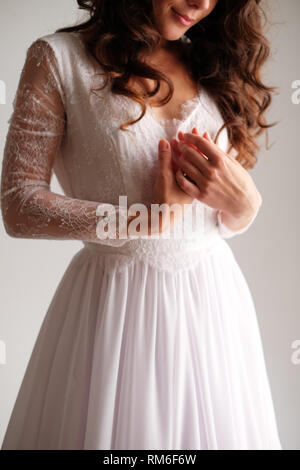 Una ragazza in un abito leggero piegato le braccia attraverso il suo torace. Le mani della sposa, delicatamente rosa, abito sposa. La mattina di nozze. Foto Stock