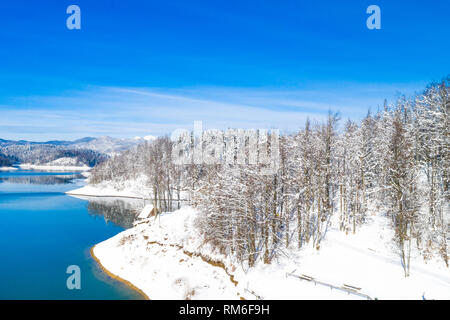 Inverno bellissimo paesaggio panoramico in montagna, lago Lokvarsko in Croazia, boschi sotto la neve nella regione di Gorski kotar e Risnjak mountain in background Foto Stock