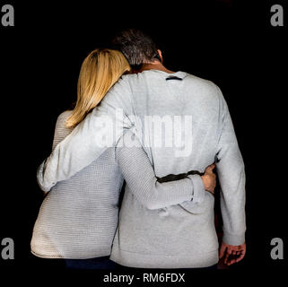 Matura in amore abbracciarsi contro uno sfondo nero Foto Stock